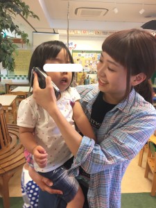 園の内線でにこにこ組(2歳児クラス)の女の子が電話をしています。